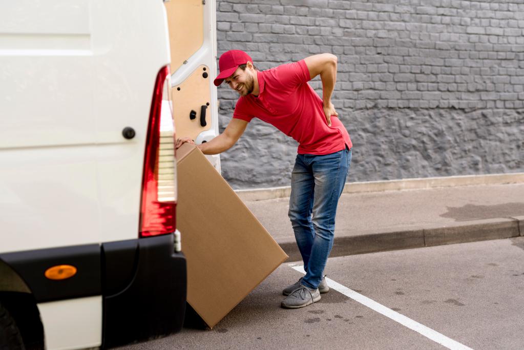 delivery man loading car with package