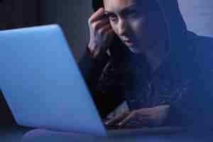 young woman breaching network security system stealing data from laptop night