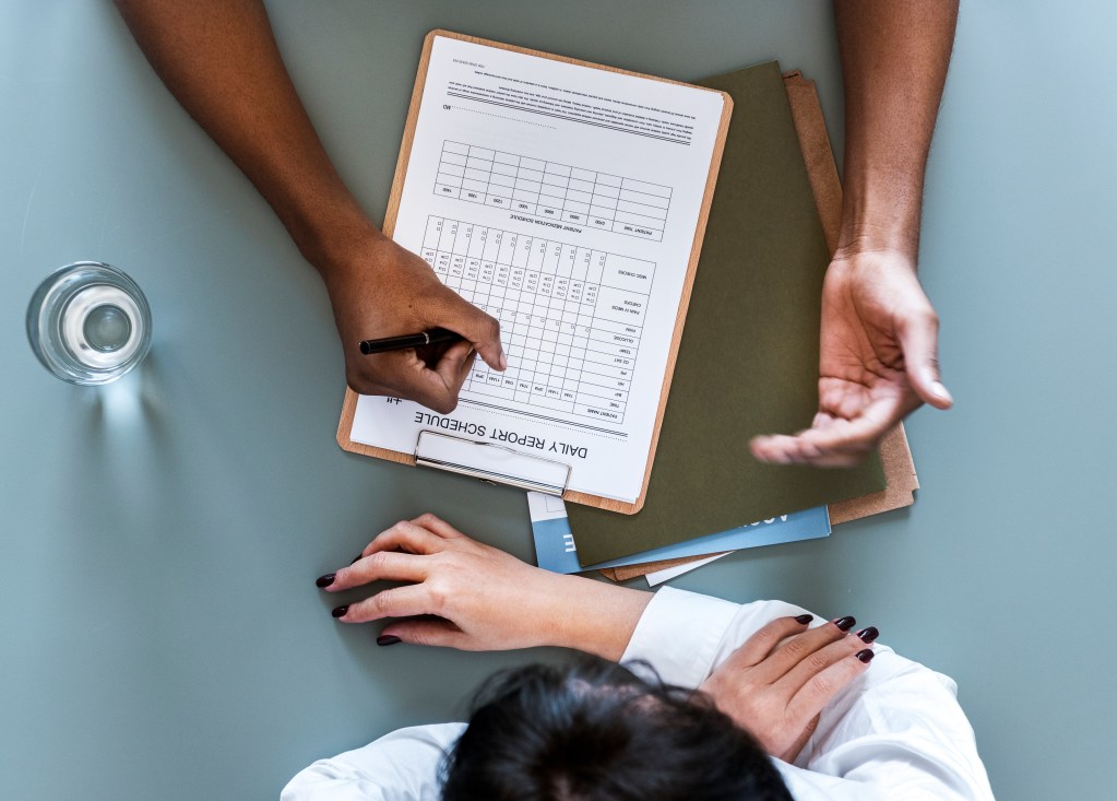 aerial view doctor writing patient daily report checklist
