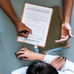 aerial view doctor writing patient daily report checklist