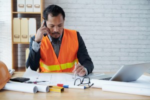 asian male construction firm executive sitting office talking phone