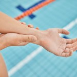 hand wrist pain swimmer by pool gym closeup after emergency accident training fitness water swimming athlete with injury arthritis tendinitis her arm