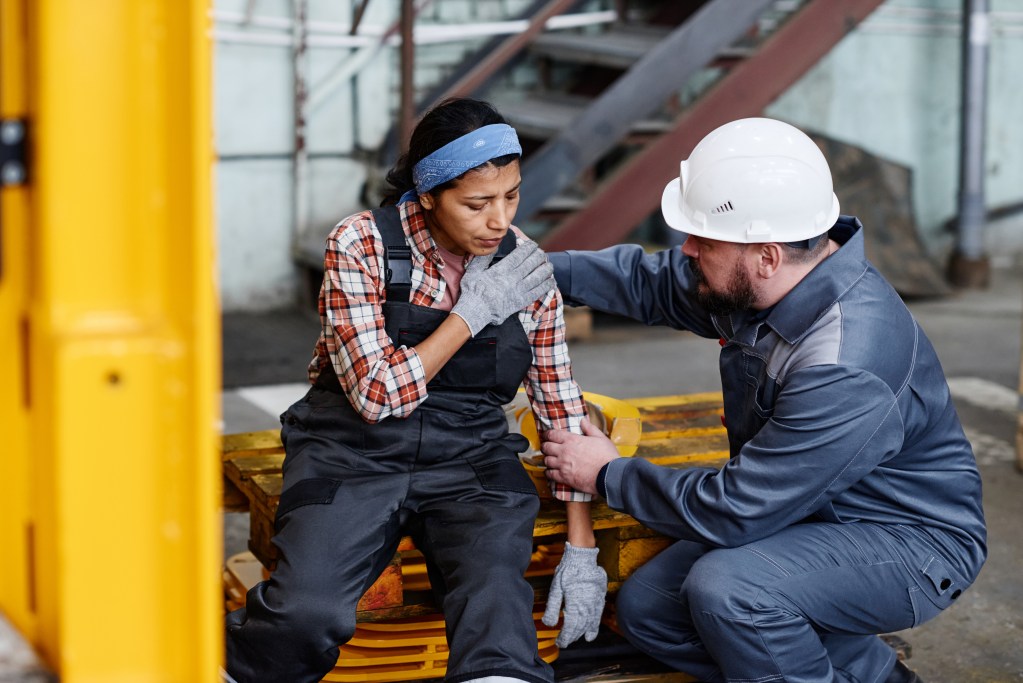 mature foreman workwear giving first aid female subordinate pain