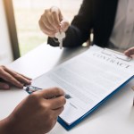 hand real estate agent passes key new homeowners office with buyer house concept